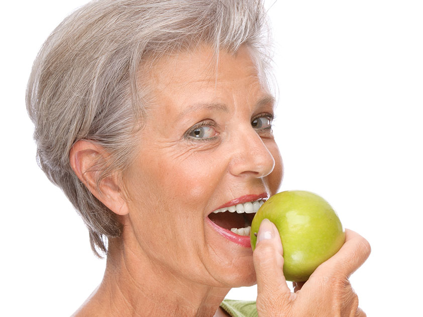Lady biting in apple with dentures